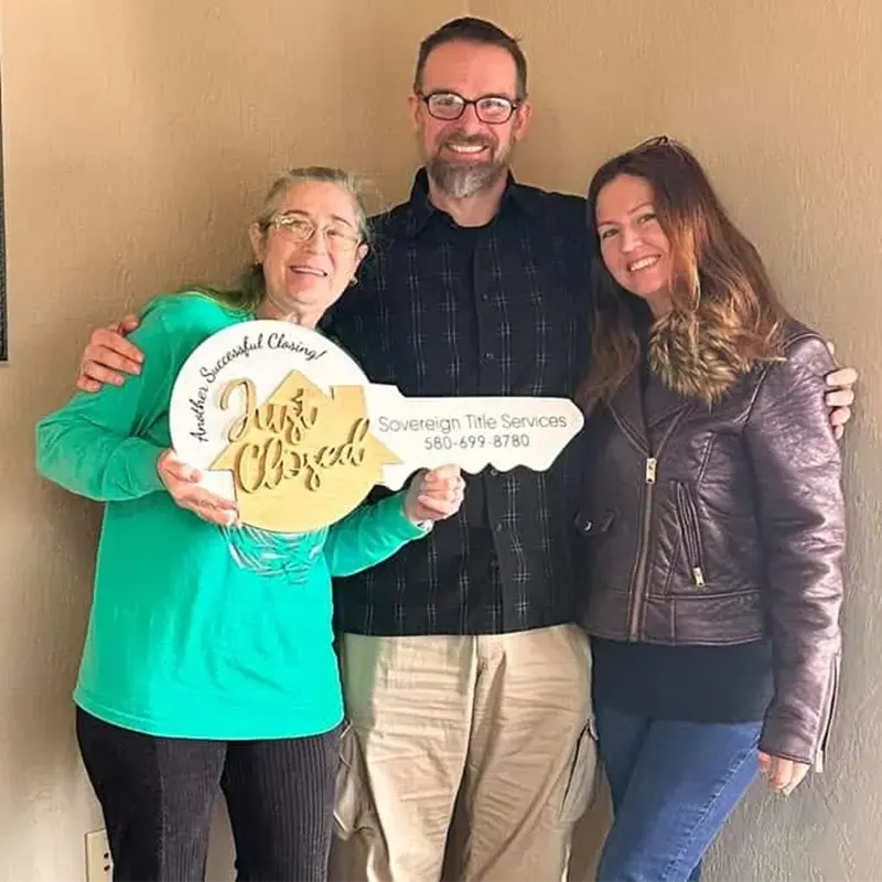 Brittany McConnell with two clients holding a “Just Closed” sign on closing day